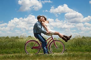 Um casal feliz, numa bicicleta. Como elogios fortalecem um relacionamento?